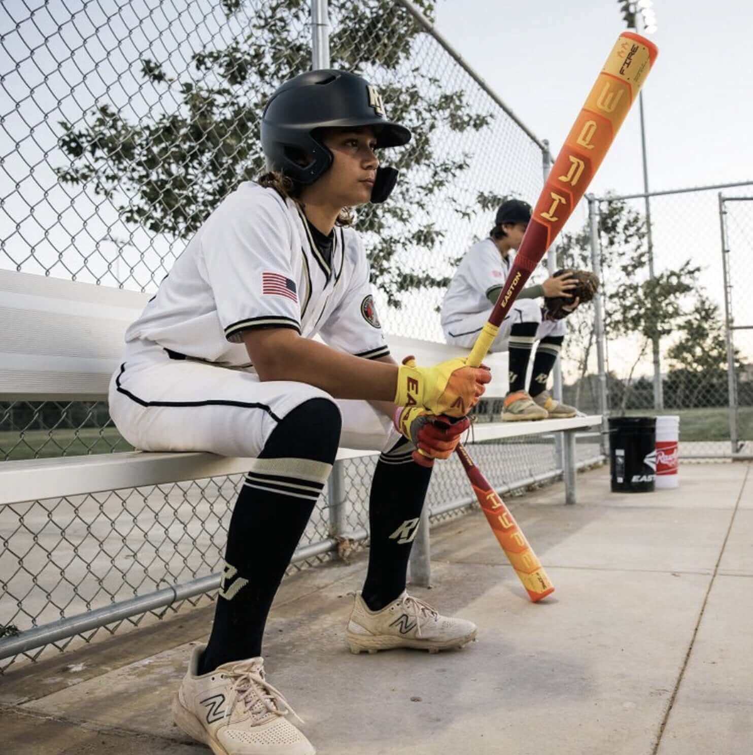 A young baseball player sitting with a bat, learning how to size a baseball bat for the perfect fit.