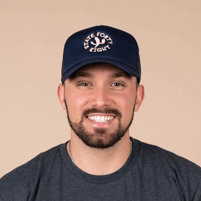State Forty Eight Foam Trucker Hat in navy with playful cactus design, modeled by a smiling man.