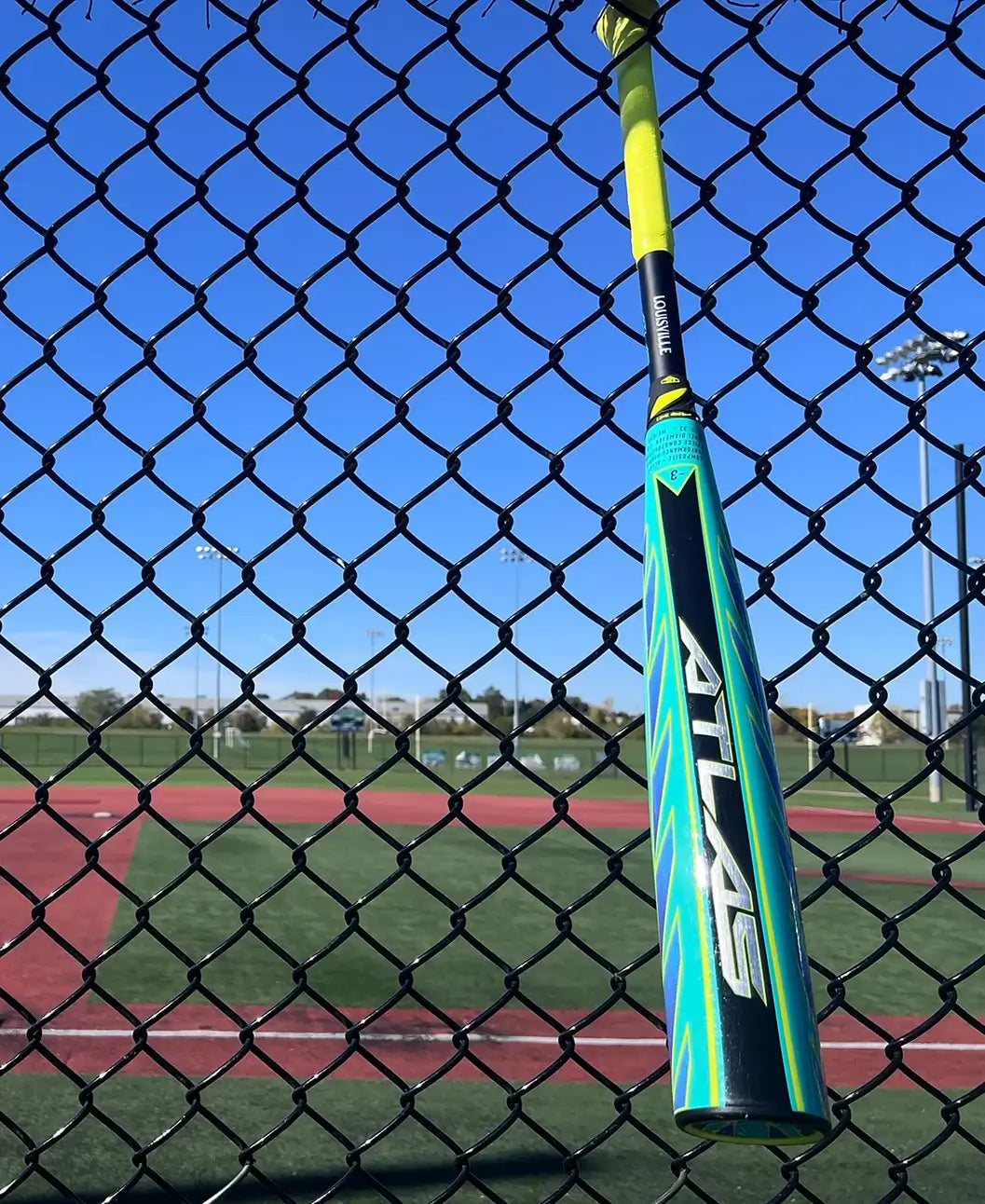 2026 Louisville Slugger Atlas Hybrid Green (-3) BBCOR Baseball Bat hanging on fence