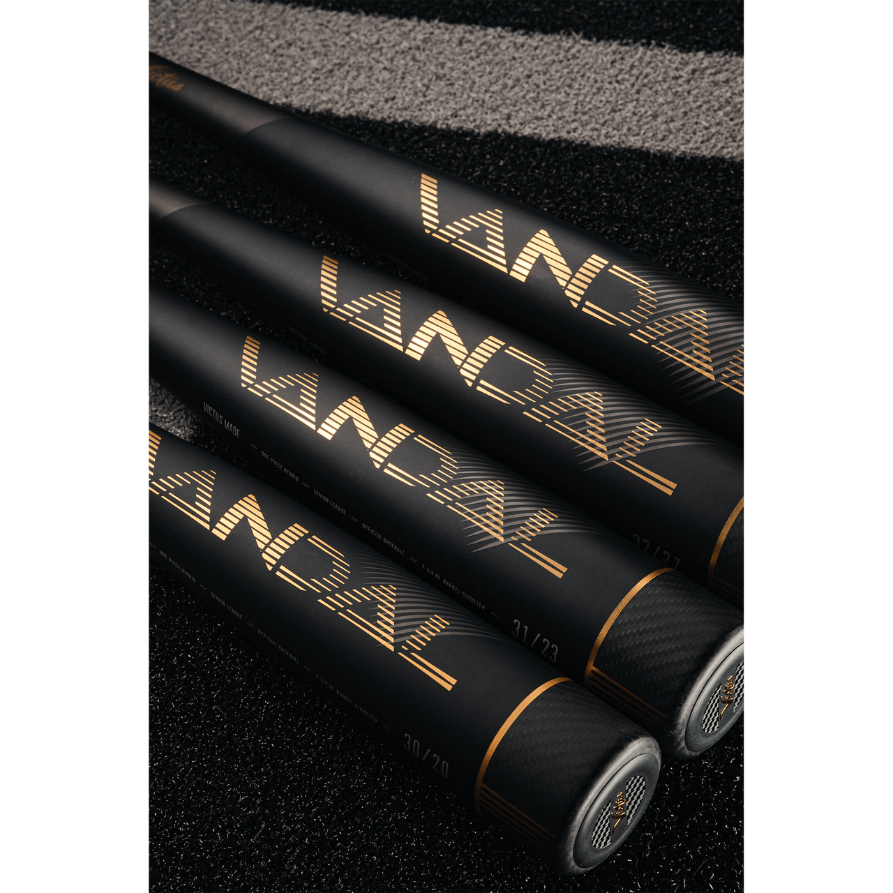 Three Victus Vandal 2 baseball bats showcasing sleek black design with gold branding on a textured surface.