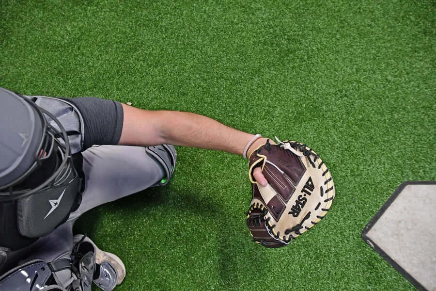 Player demonstrating the All-Star S7 ELITE™ Catcher's Mitt on turf, showcasing its design and deep pocket construction.