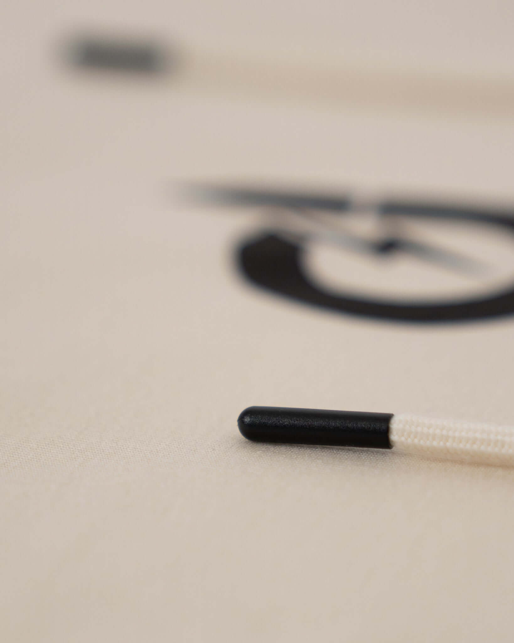 Close-up of a black-tipped cord on a light background, showcasing intricate design details.