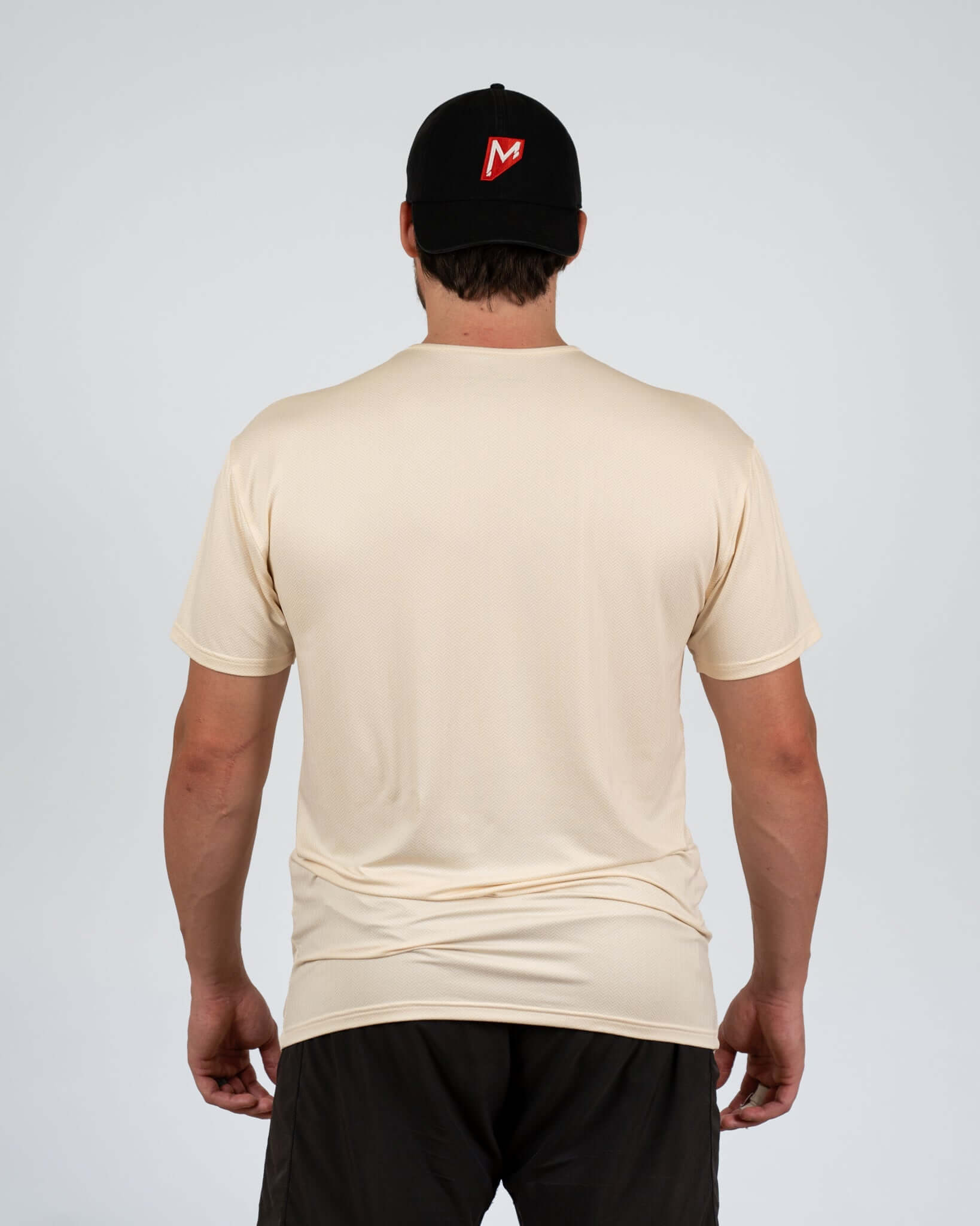Back view of a man wearing the Momentum Tan Recovery Tee, showcasing its relaxed fit and soft fabric.
