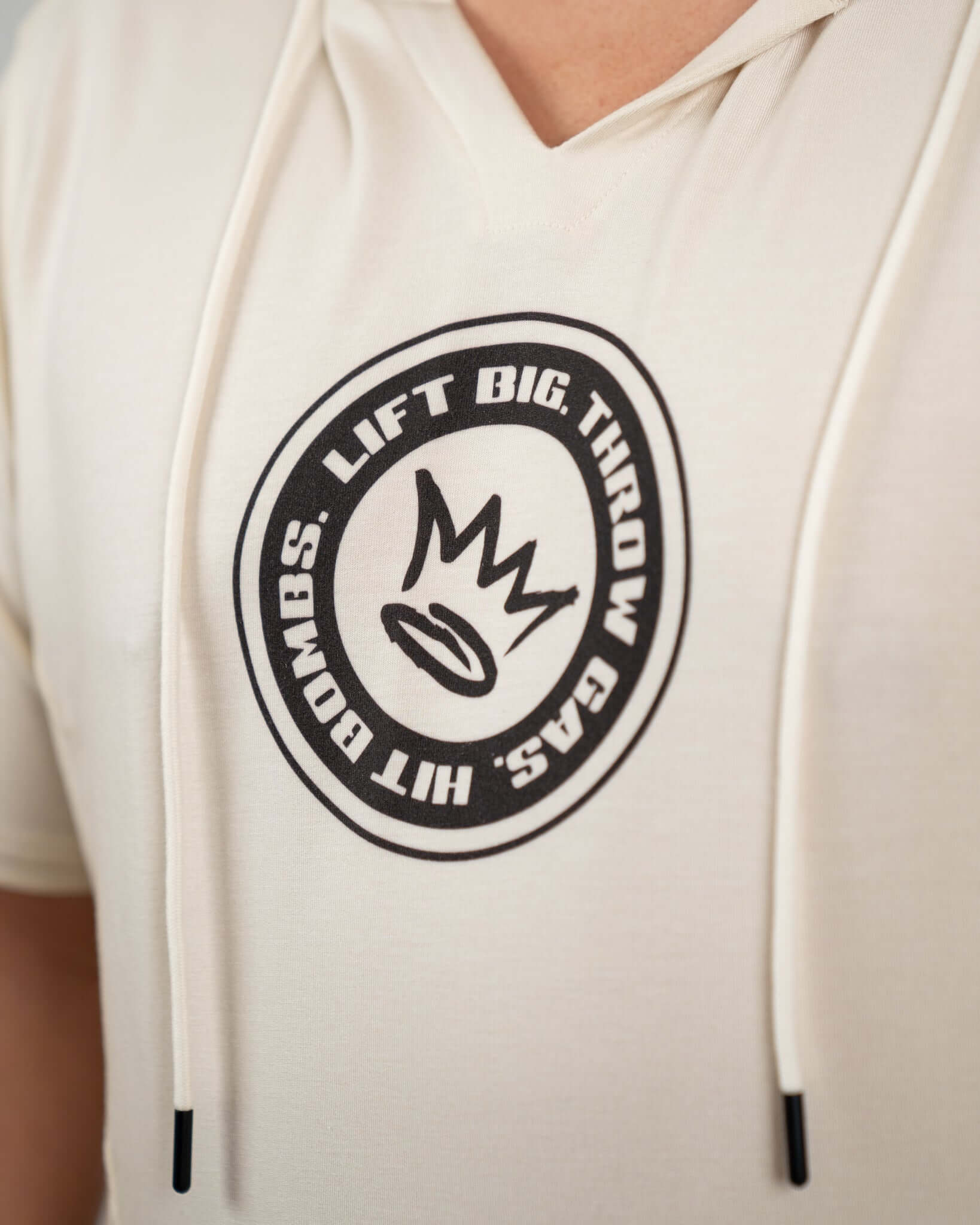 Close-up of King of Juco Tan Short Sleeve Hoodie featuring a stylish logo with motivational text.