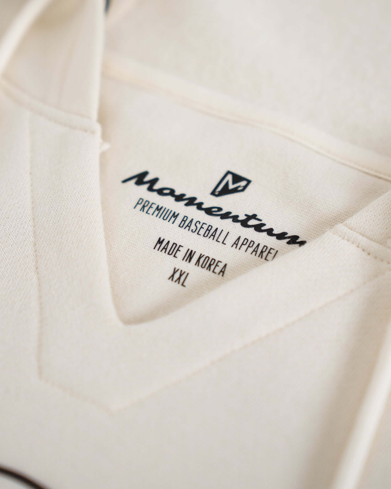 Close-up of the Momentum Baseball Apparel label, showcasing premium fabric and XXL size, made in Korea.