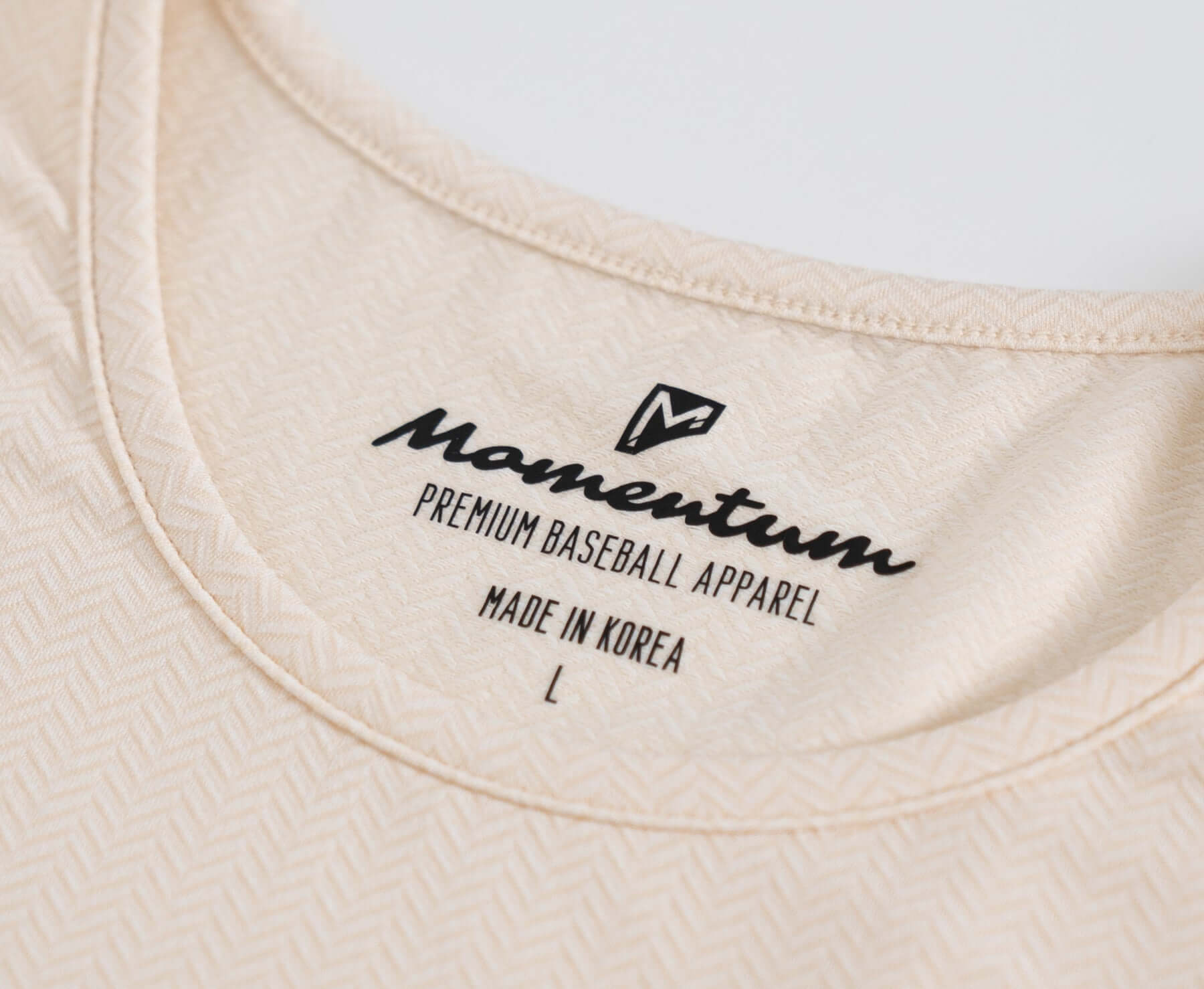 Close-up of the Momentum Tan Recovery Tee label showing premium fabric and care instructions.