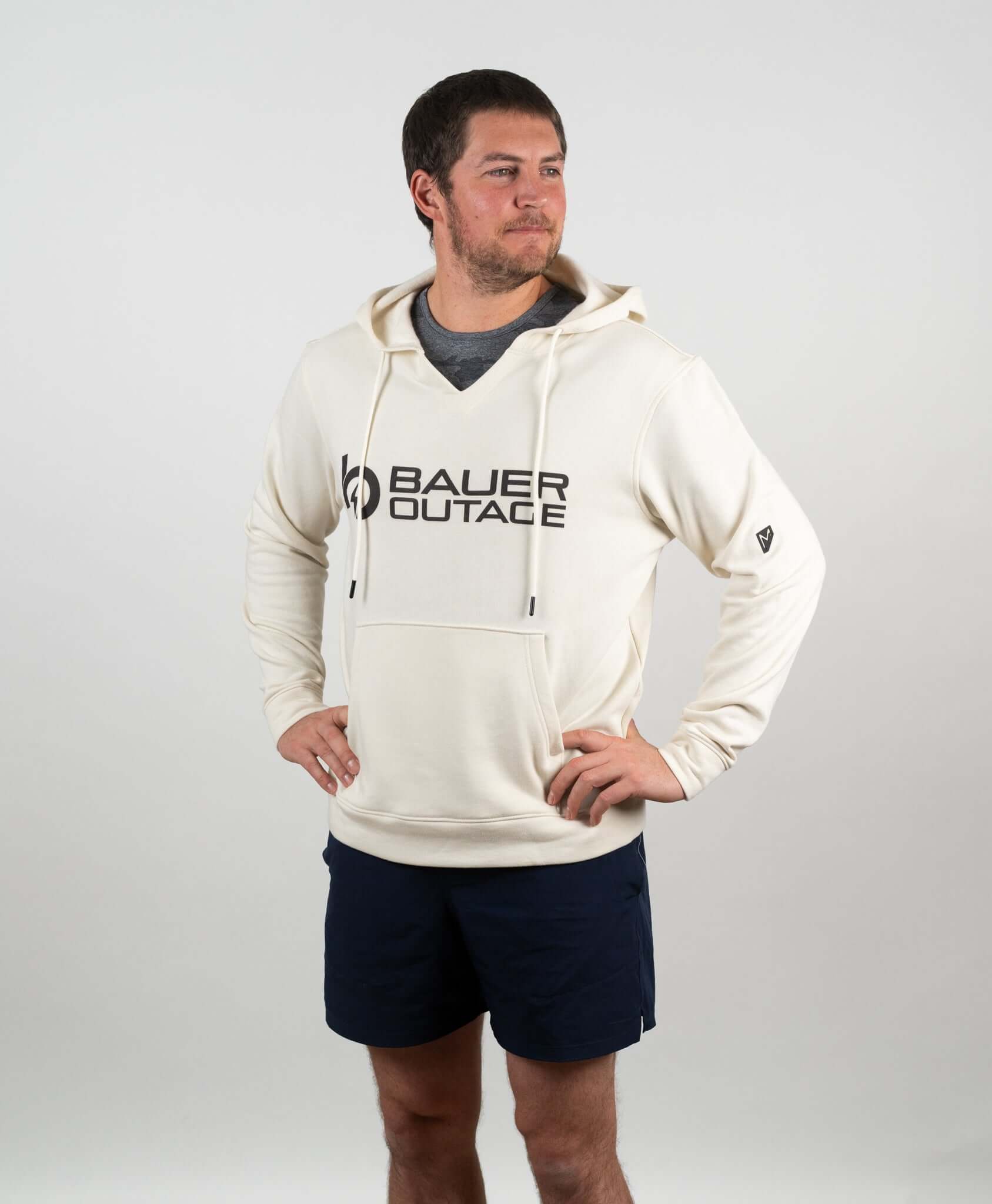 Man wearing Bauer Outage tan heavyweight recovery hoodie, showcasing its cozy design and stylish notch-neck collar.