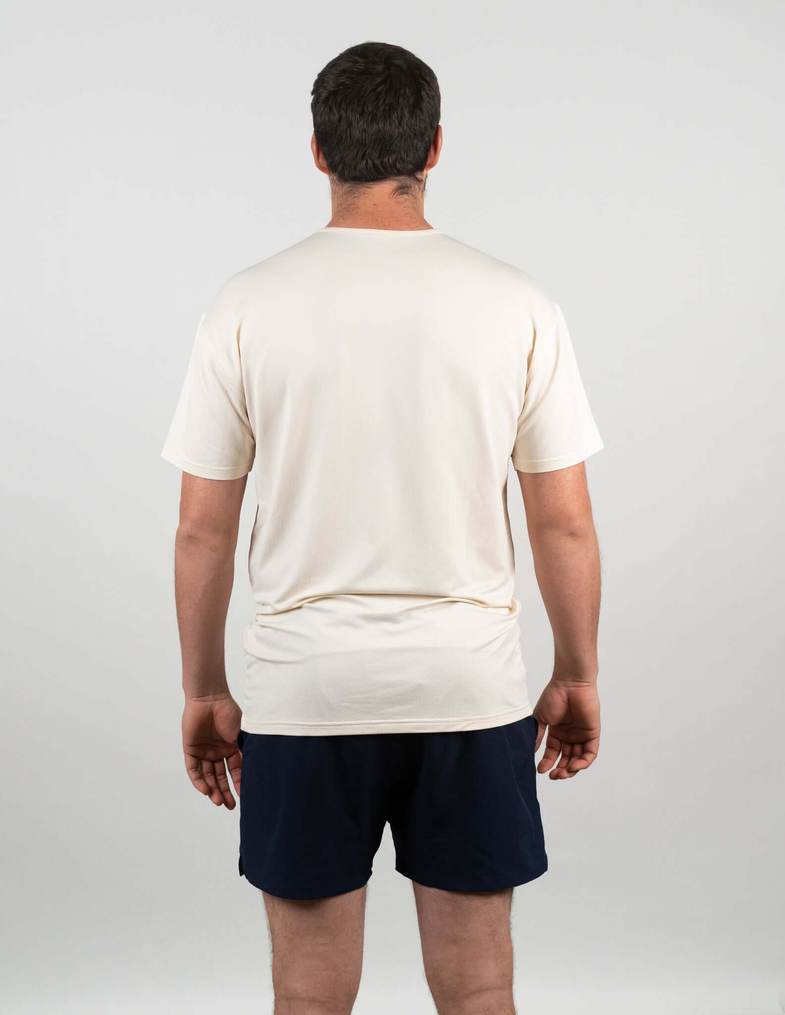 Back view of a man wearing a Bauer Outage Tan Recovery Tee, perfect for post-workout relaxation and recovery.