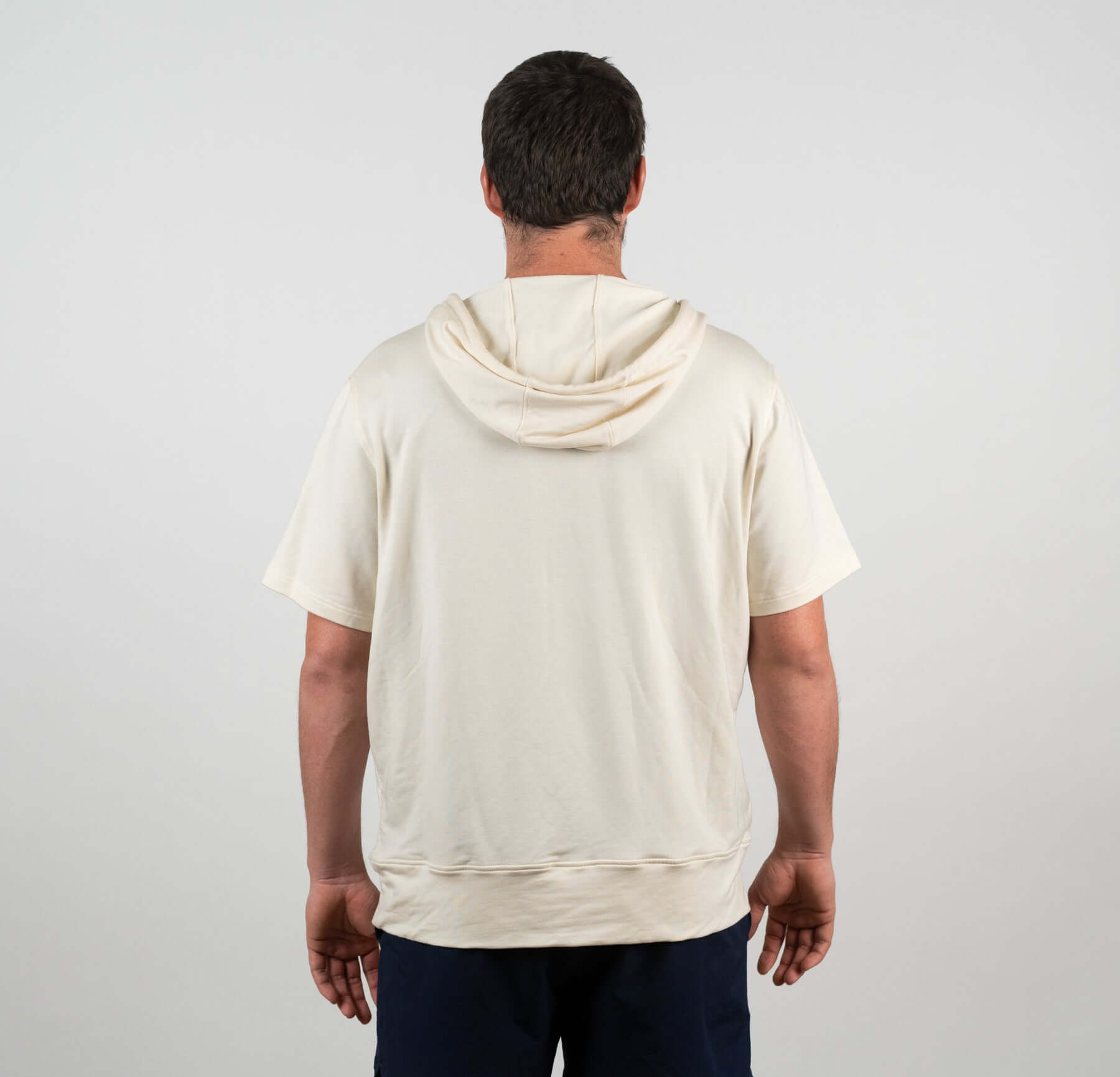 Back view of a man wearing the Bauer OutageTan Short Sleeve Hoodie, showcasing its notch-neck collar and comfortable fit.