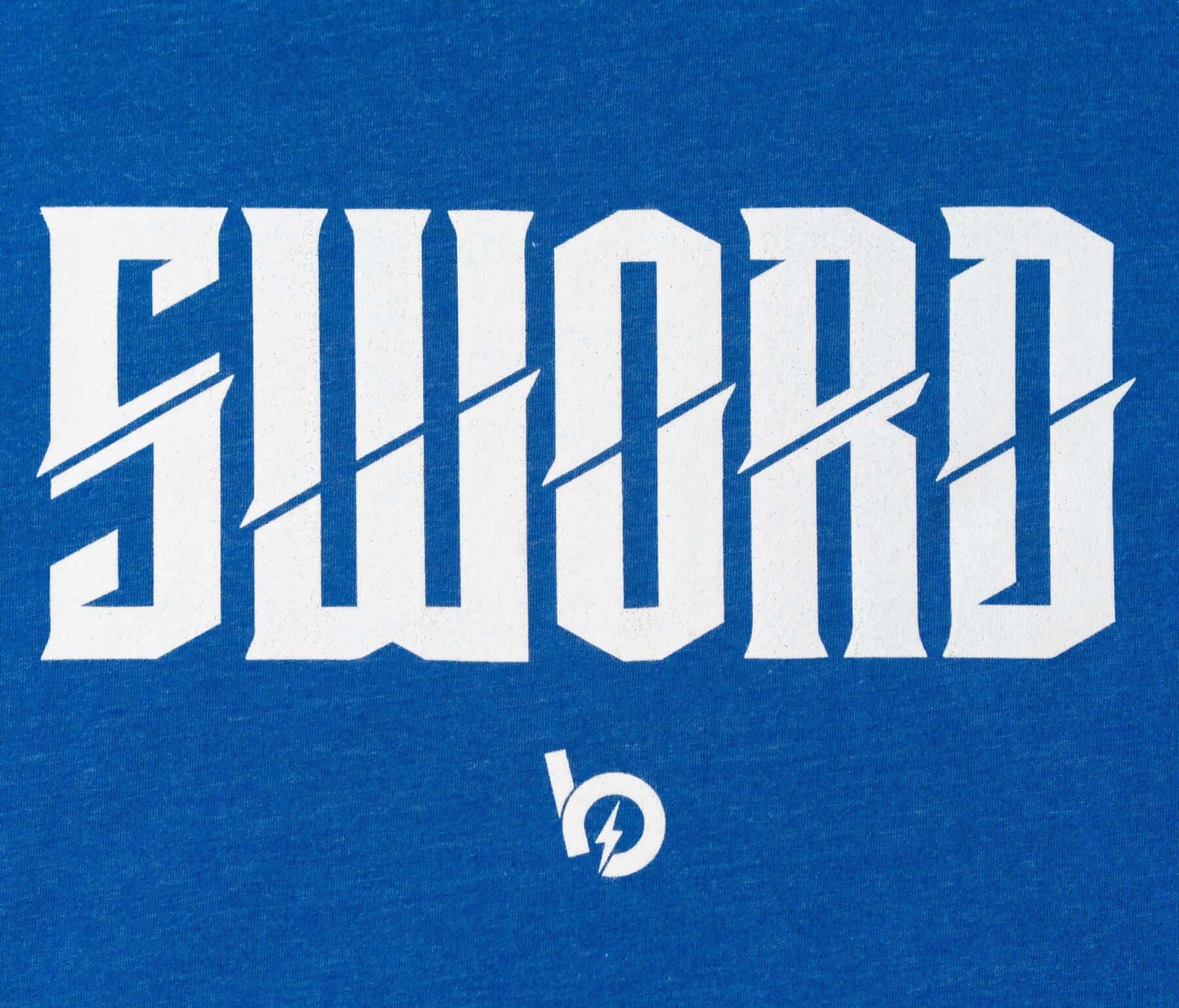 Close-up of the 'SWORD' logo on blue fabric, symbolizing strength and excellence in the Bauer Outage tee.