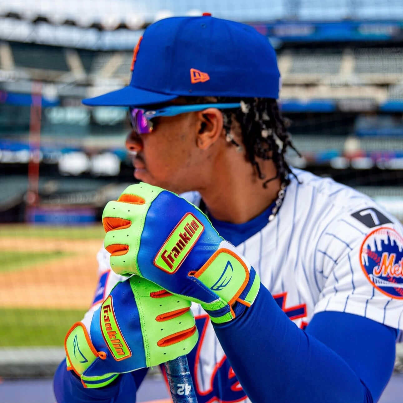 Youth player showcasing Franklin Lindor Limited Edition Pro Classic Batting Gloves in vibrant colors at baseball field.
