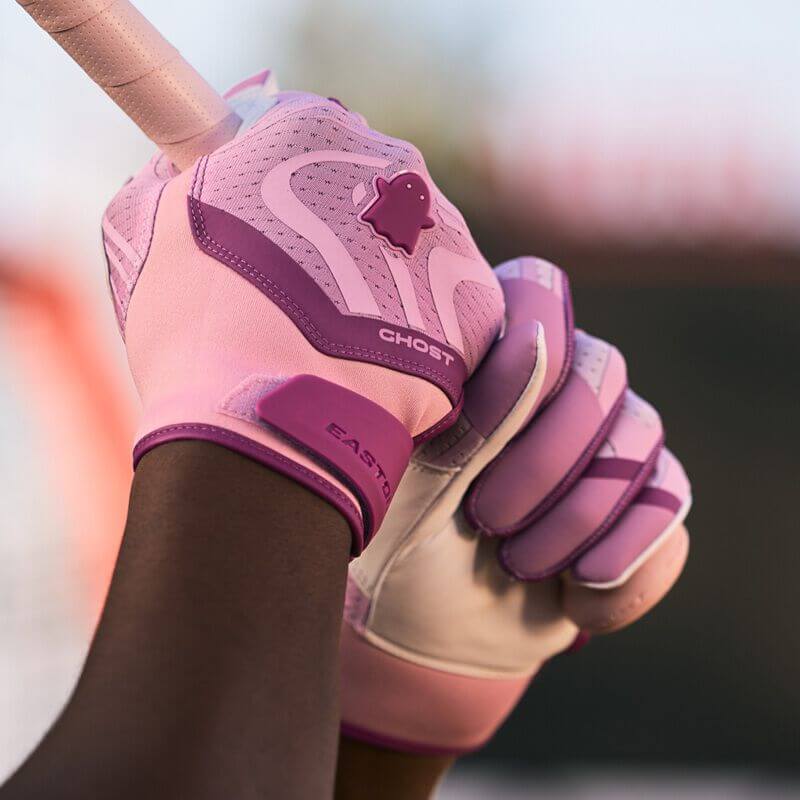 Close-up of Womens Ghost Ethos Unlimited Fastpitch Batting Gloves gripping a bat, showing pink backhand and breathable mesh design.