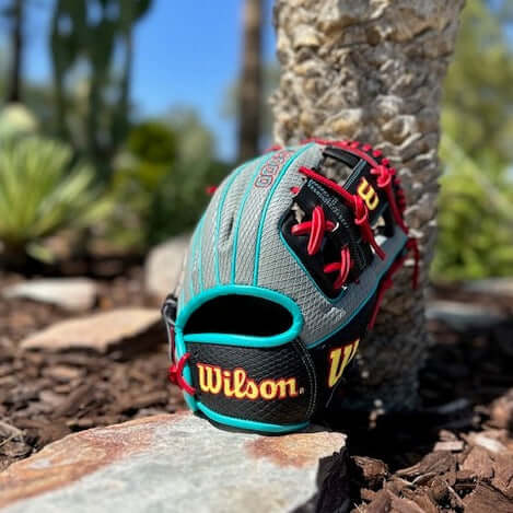 Wilson A2000 1786 11.5" baseball glove in grey and black near a stone, showcasing its detailed design and quality craftsmanship.