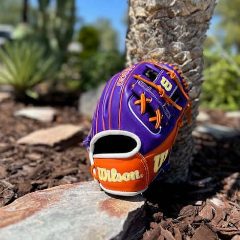 Wilson A2000 1786 11.5" baseball glove Rally The Valley in orange and purple, showcasing durability and style in natural setting.