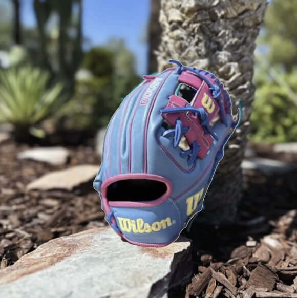Wilson A2000 1975 11.75" Pink Lemonade baseball glove on a stone surface, showcasing its vibrant colors and design.