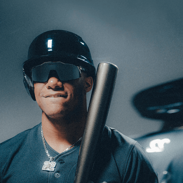 Athlete wearing black helmet and sunglasses holding a baseball bat, showcasing sporty style and readiness for the game.