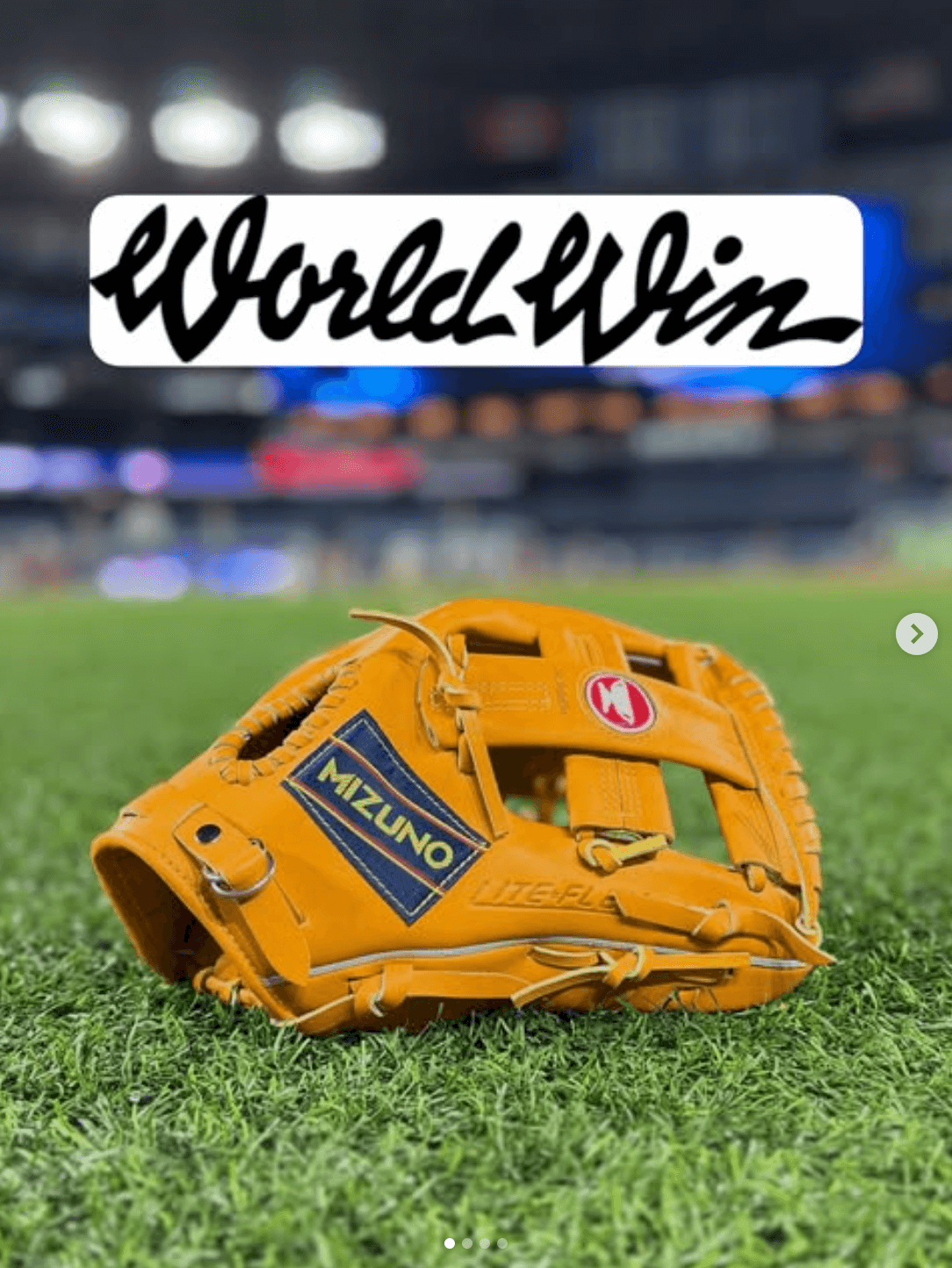 Mizuno Limited Edition World Win Infield Glove 11.5" on grass field, baseball stadium in the background.