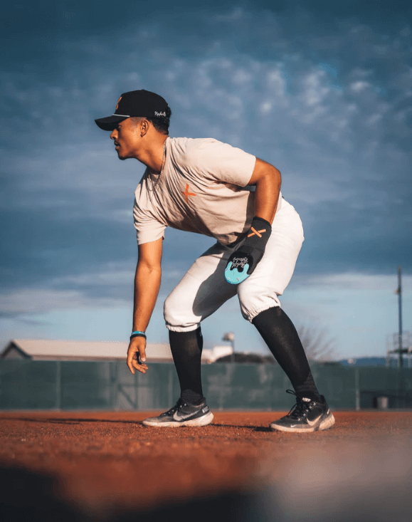 Side view of athlete wearing Pushin' P Youth Sliding Mitt - Absolutely Ridiculous Ice Cream Collection on a baseball field.