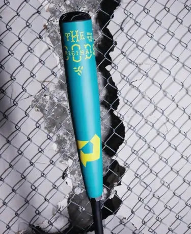 DeMarini The Goods Teal BBCOR 2025 bat showcasing its vibrant teal and neon yellow design against a chain link background.