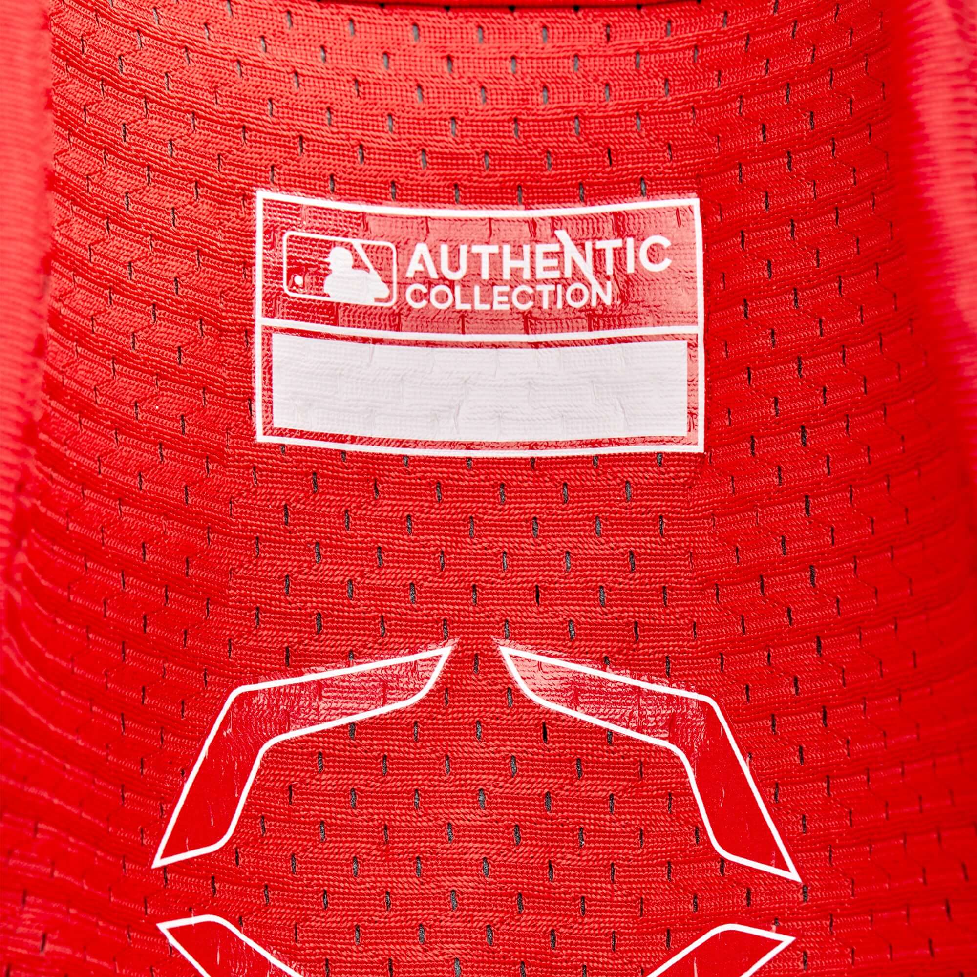 Close-up of the AUTHENTIC COLLECTION label on a red fabric, showcasing high-quality baseball apparel.