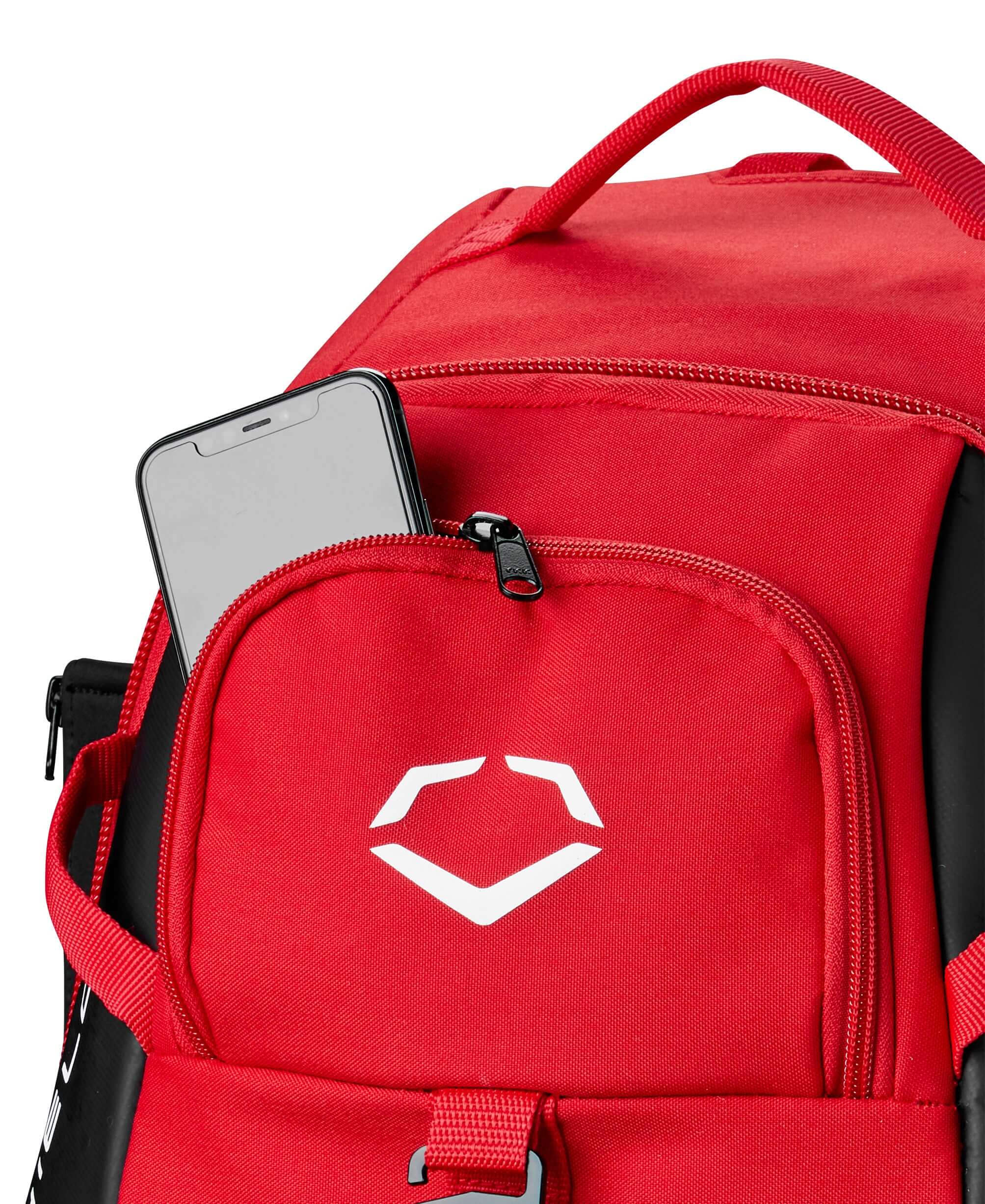 Close-up of Evoshield Recruit Backpack showing a smartphone in the front pocket, featuring durable red nylon fabric.