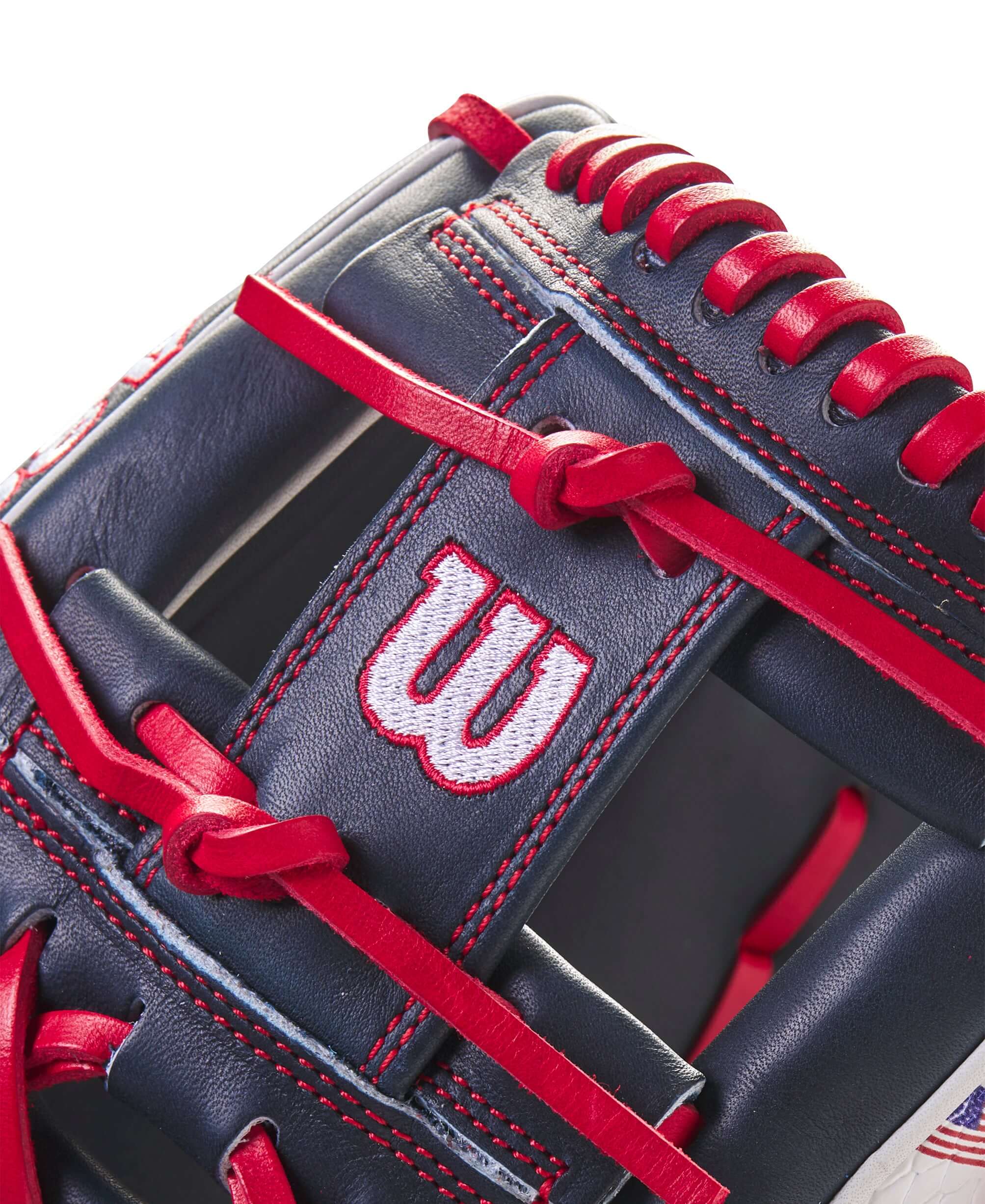 Close-up of the Wilson A2000 July 2023 glove featuring red and navy design with embroidered logo and leather lacing.