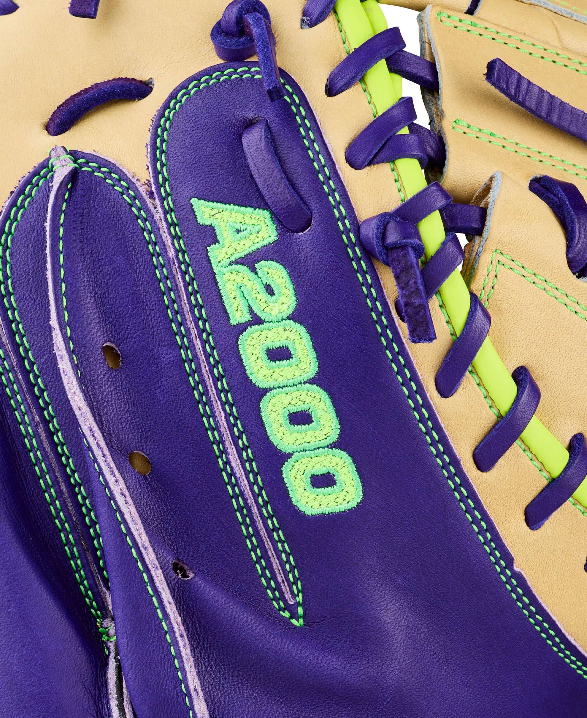 Close-up of Wilson Spring 2026 A2000 FPCM23 glove web detail with purple and tan leather, purple lacing, and lime green stitching.