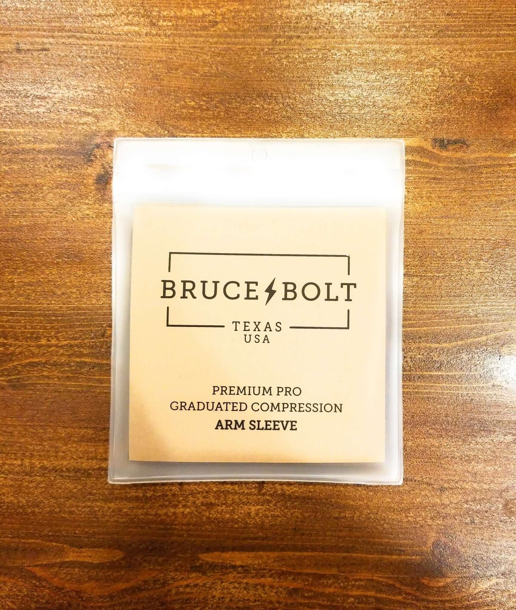Bruce Bolt graduated compression arm sleeve packaging on wooden surface, highlighting premium pro features.