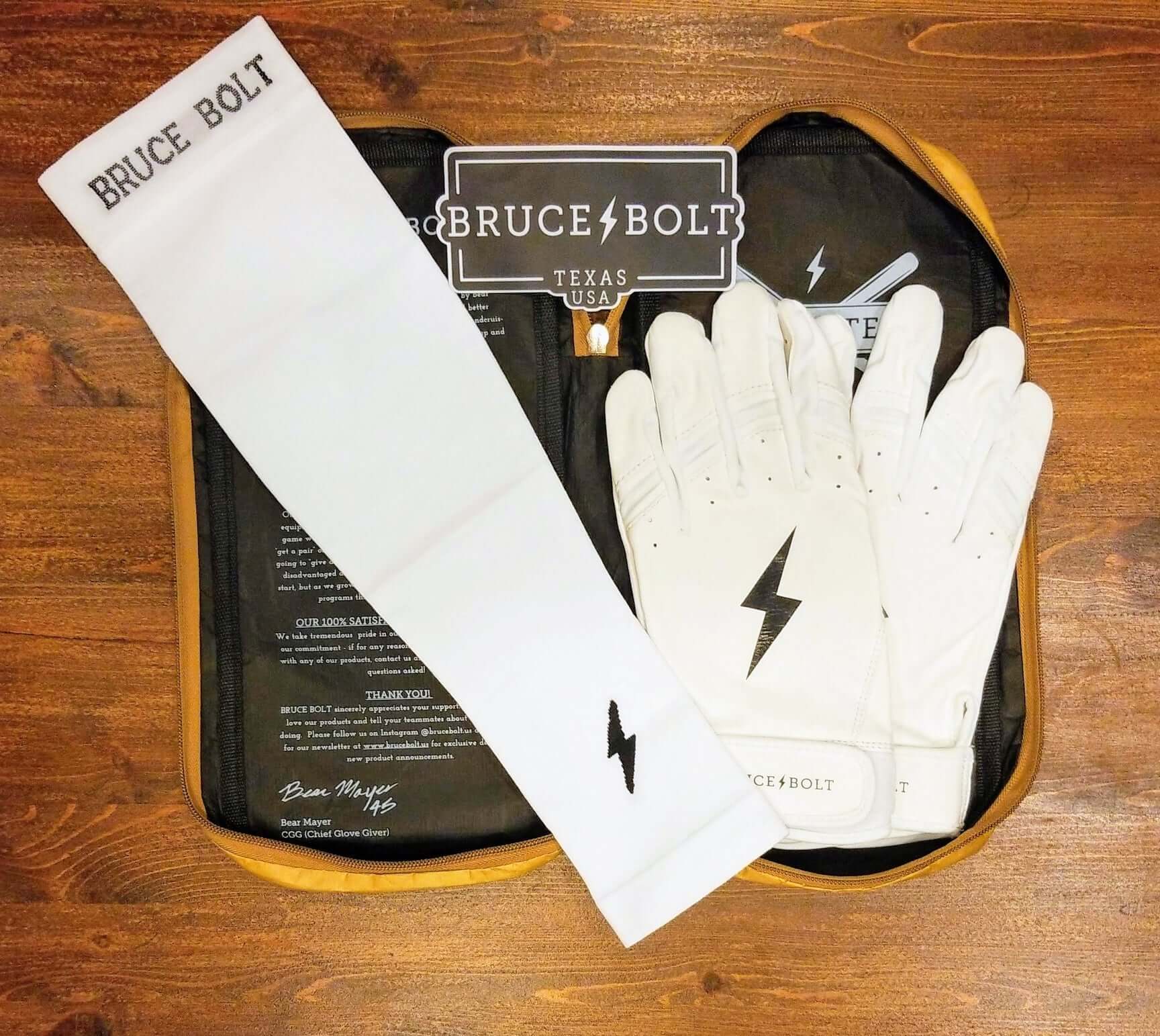 Bruce Bolt graduated compression arm sleeve in white with matching white gloves on a wooden surface.