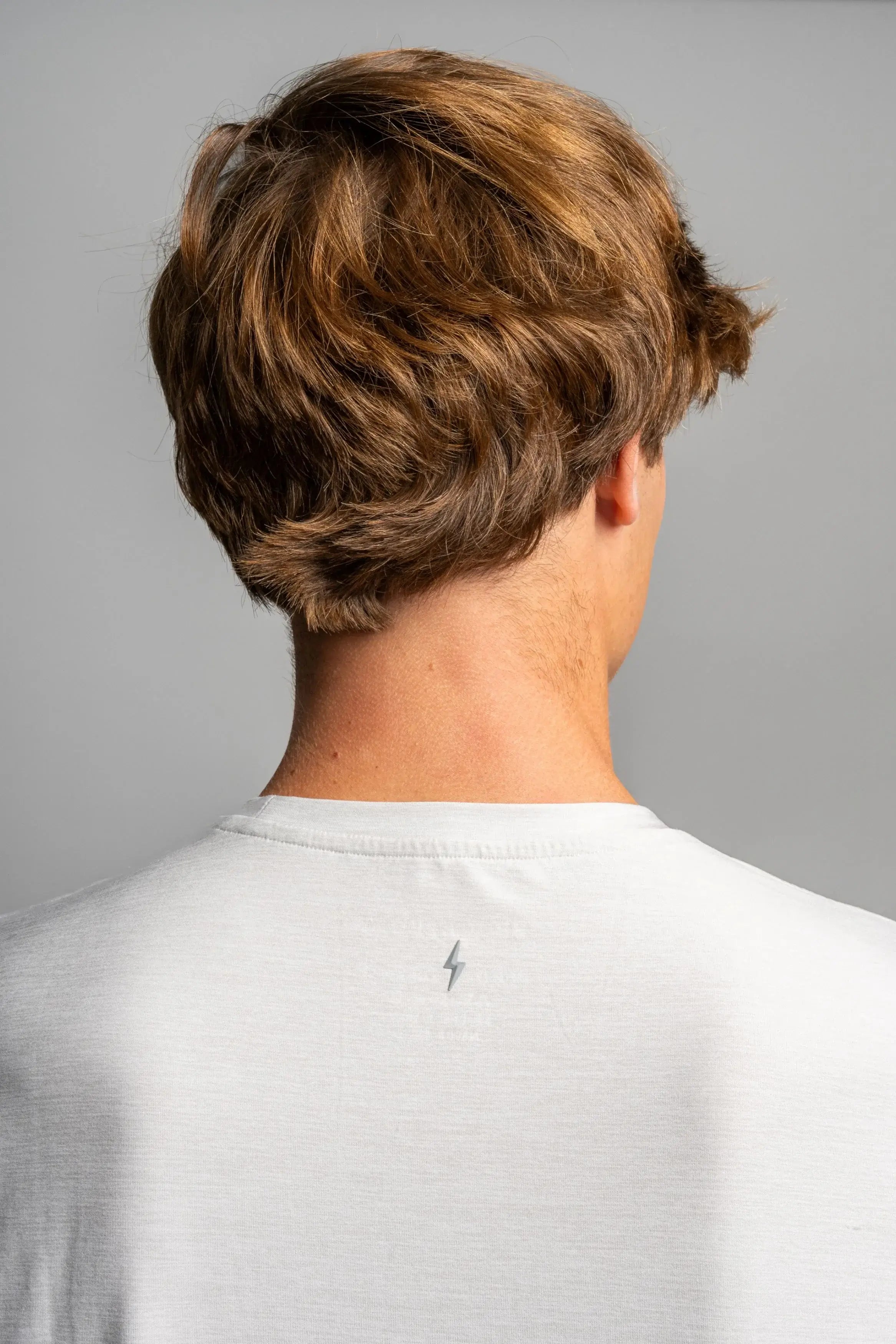 Back view of a model wearing the Bruce Bolt SuperSoft T-Shirt, showcasing its unique lightning bolt logo on a grey fabric.