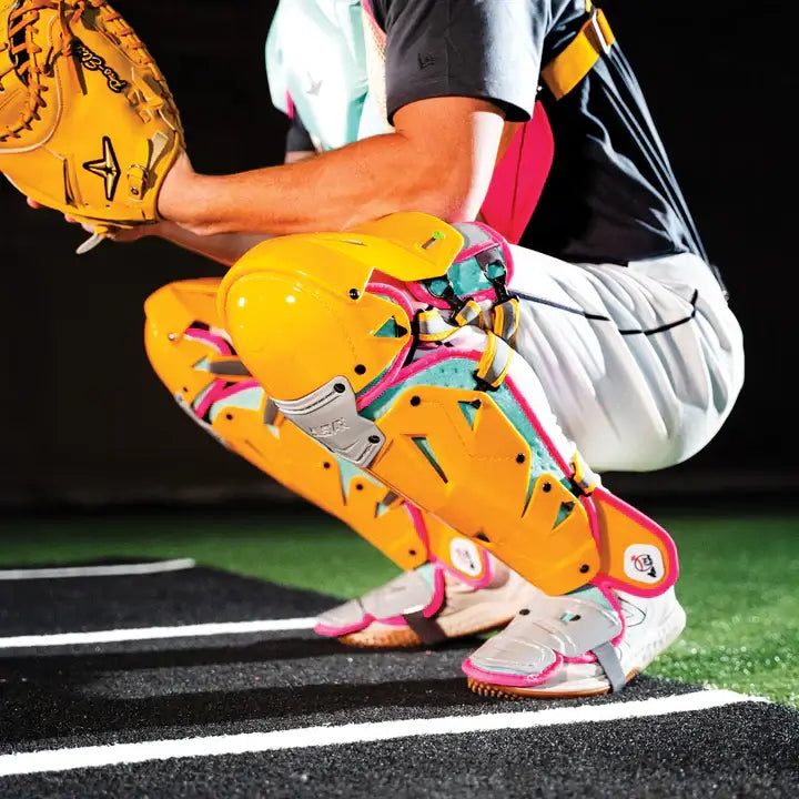 Side view of All-Star MVP-Pro Short Fuse Catcher's Kit in Yellow/Pink/Seafoam, showing knee and shin protection with vibrant colors.