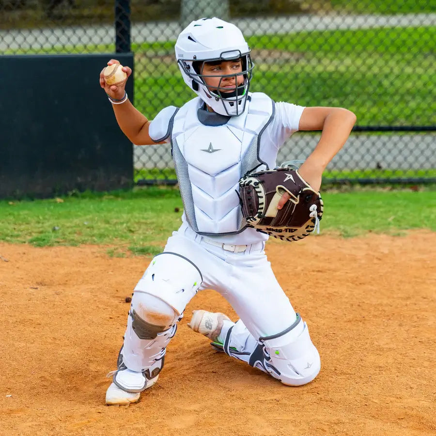 Player wearing All-Star MVP-PRO™ Catcher Leg Guards, Black/Black, Small, in action blocking a pitch on the field.