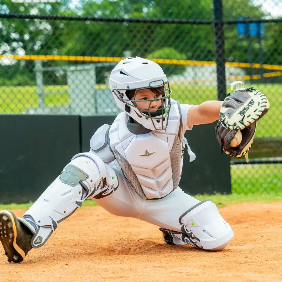 Catcher wearing All-Star MVP-PRO™ Chest Protector / NOCSAE / Intermediate BK/BK, squatting on field, showcasing gear in action.