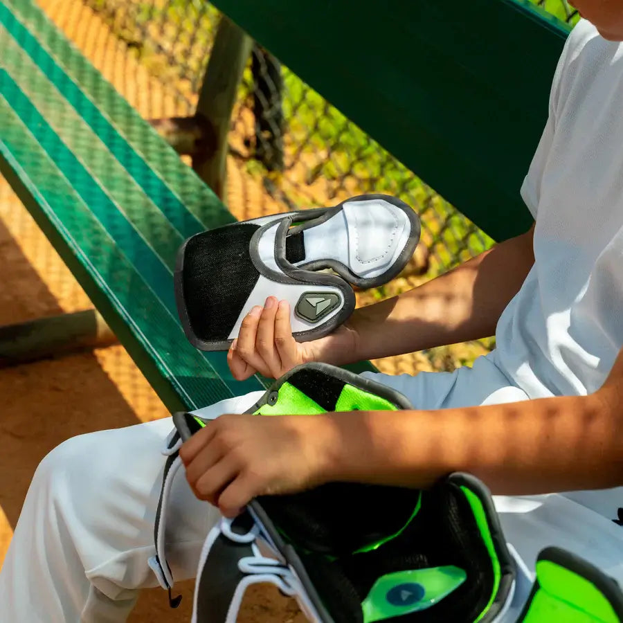 Child holding All-Star MVP-PRO™ Catcher Leg Guards | Black/Black | Small with visible interior padding and SHIFT™ feature.