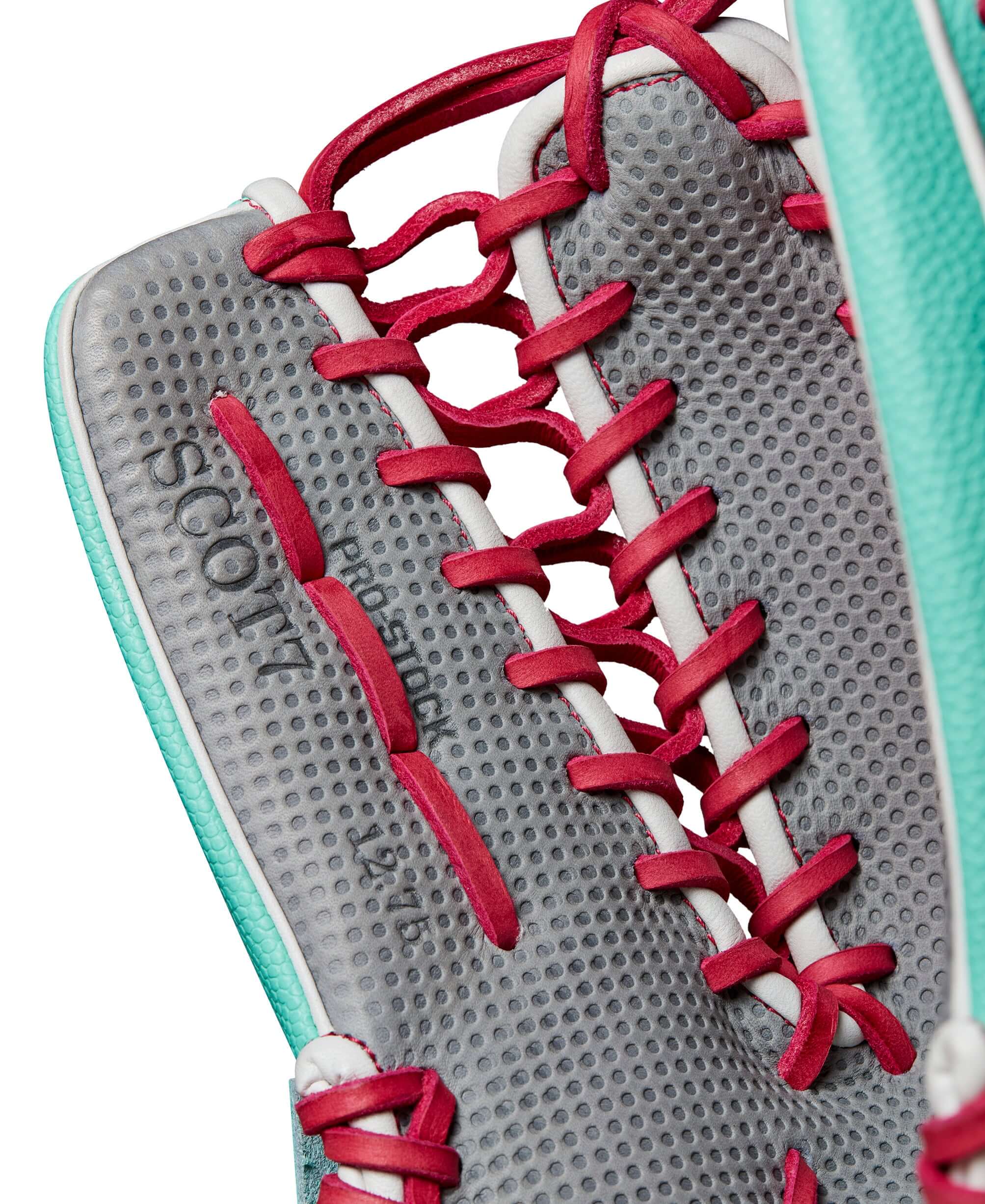 Close-up of Wilson A2000 SCOT7SS glove's interior, showcasing teal SuperSkin™ and pink lacing for secure grip.