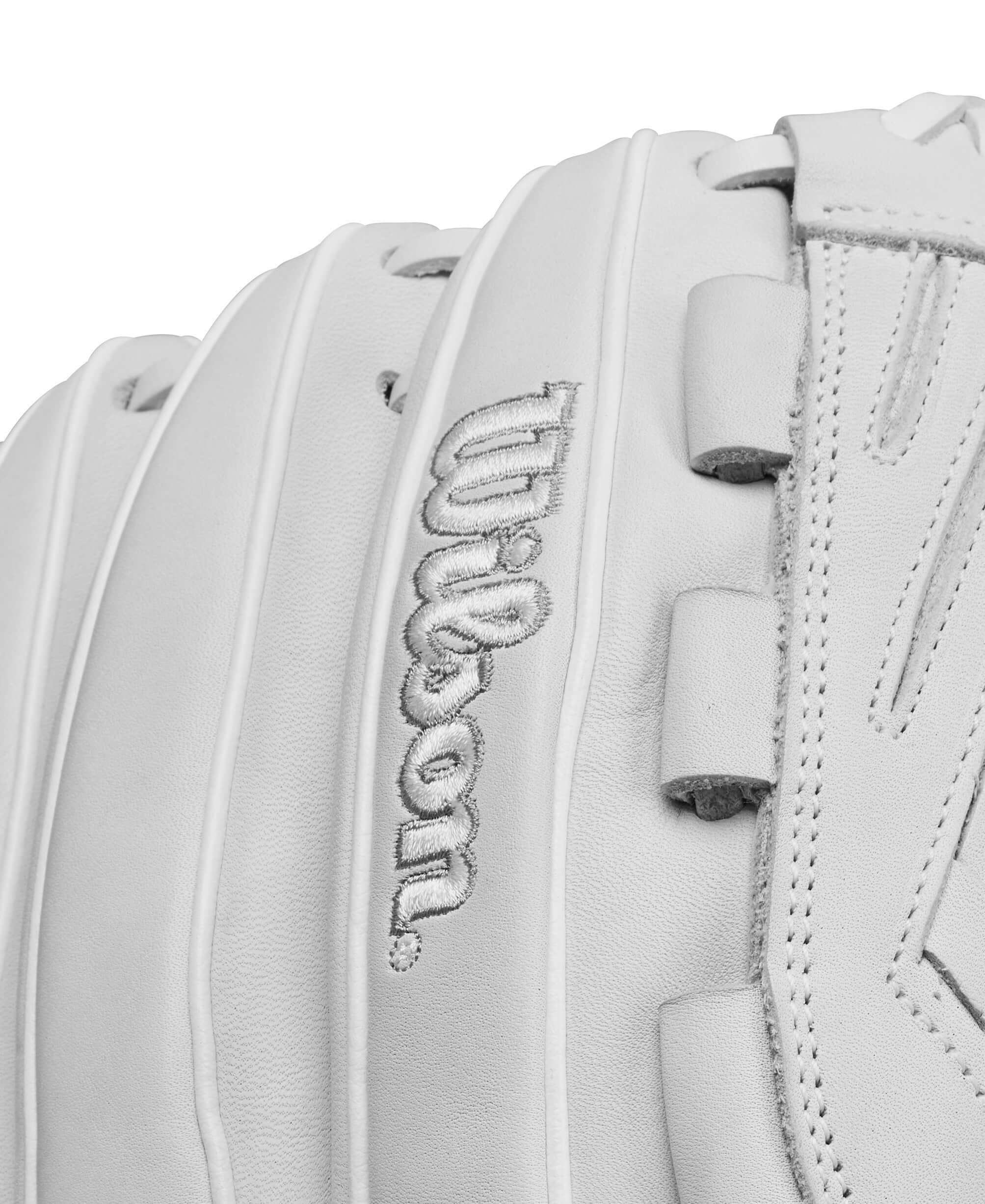Close-up of the Wilson logo on a white fastpitch softball glove, showcasing quality craftsmanship.