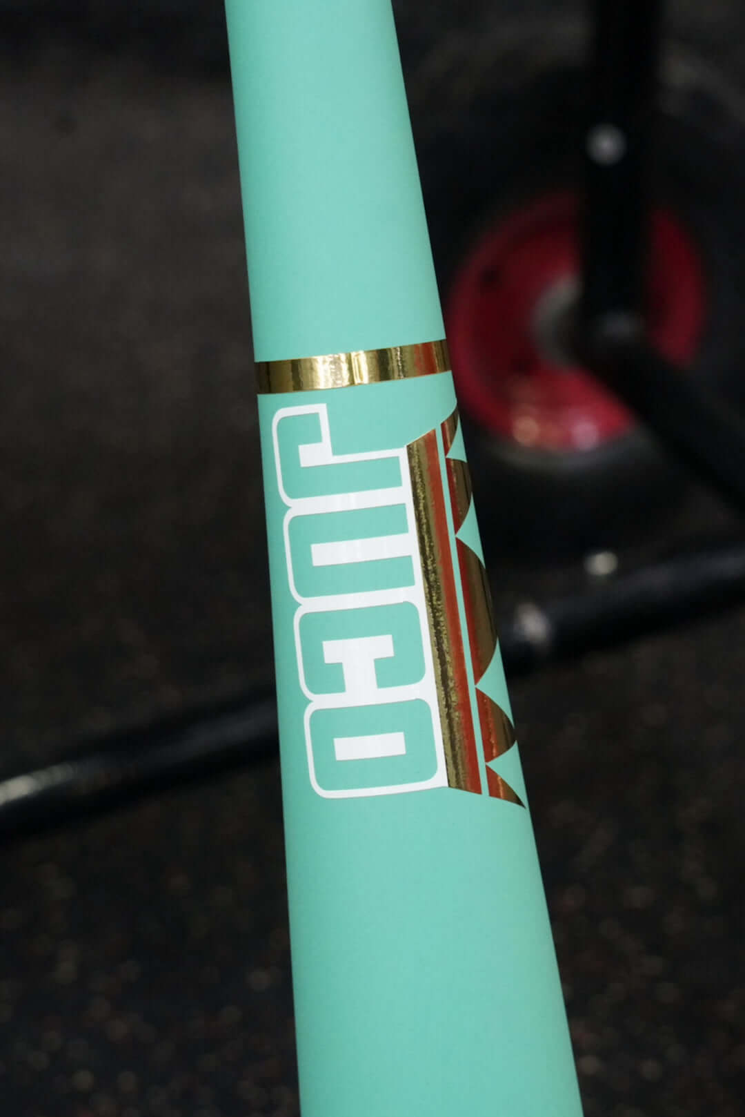 Close-up of the flared handle on the King Of Juco V.2 matte mint wood bat featuring the JUCO logo and gold accents.