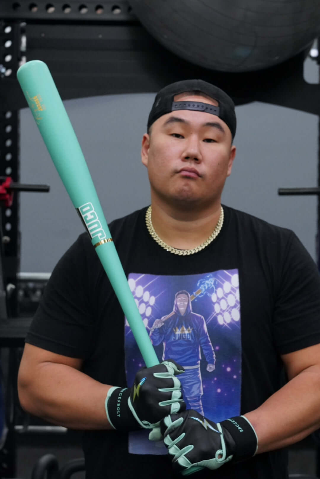 Athlete holding a King Of Juco V.2 Matte Mint Wood Bat, ready for training in a gym setting.