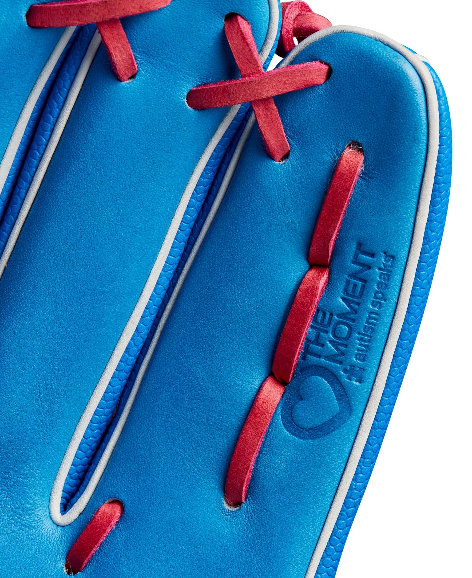 Close-up of the Wilson 2024 Autism Speaks A2000 PF92SS glove showing blue leather, red lacing, and "The Moment" logo.