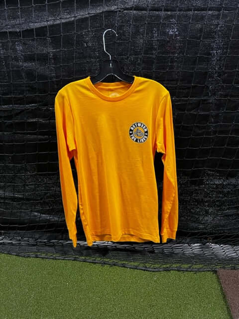 Long sleeve yellow t-shirt with logo on chest hanging against a black net backdrop. Perfect for casual wear.