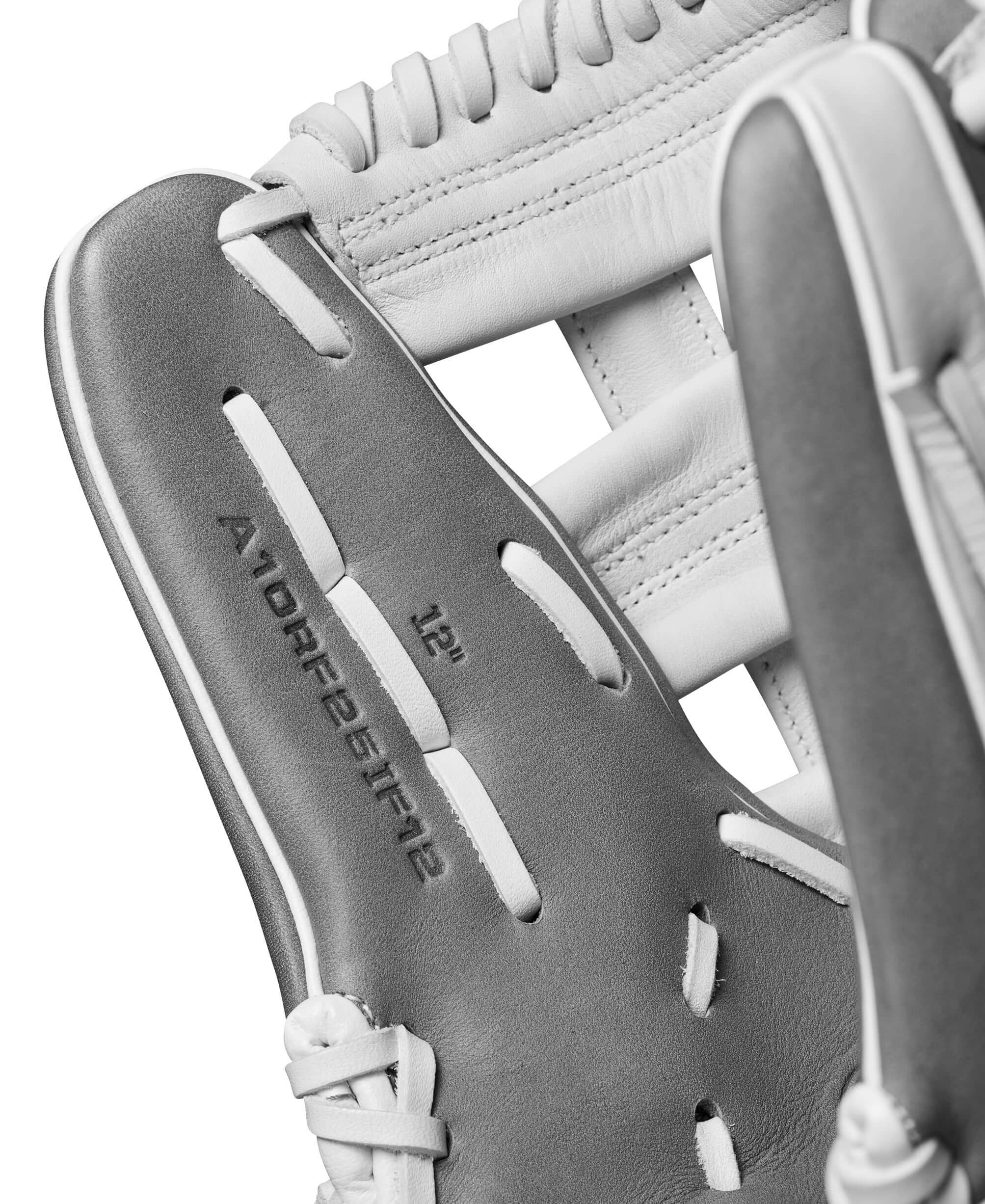 Close-up of Wilson A1000FP IF12 12" fastpitch softball glove in white and grey, showing intricate stitching and materials.