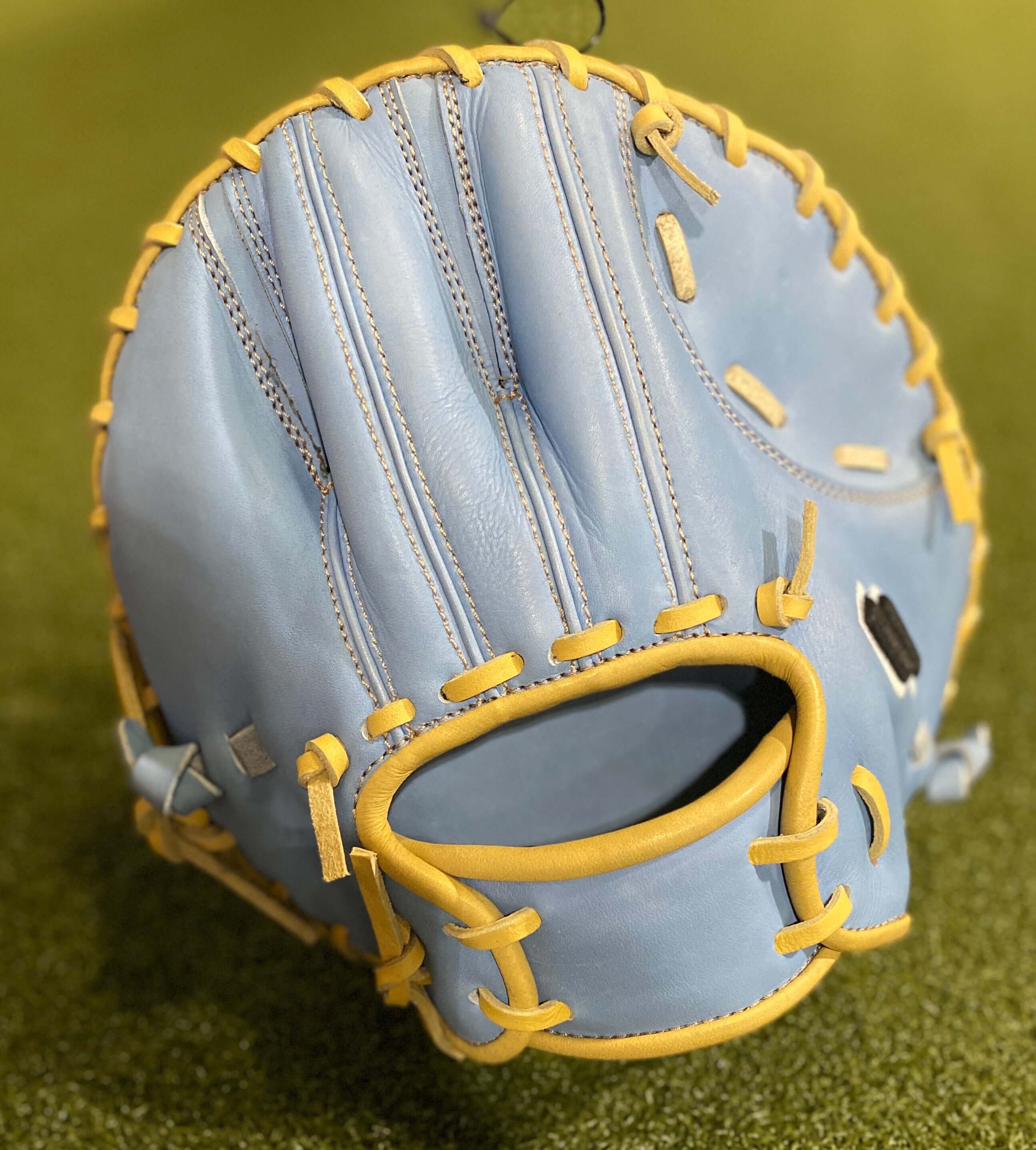 Light blue baseball glove with yellow stitching, showing a sleek design and high-quality leather craftsmanship.