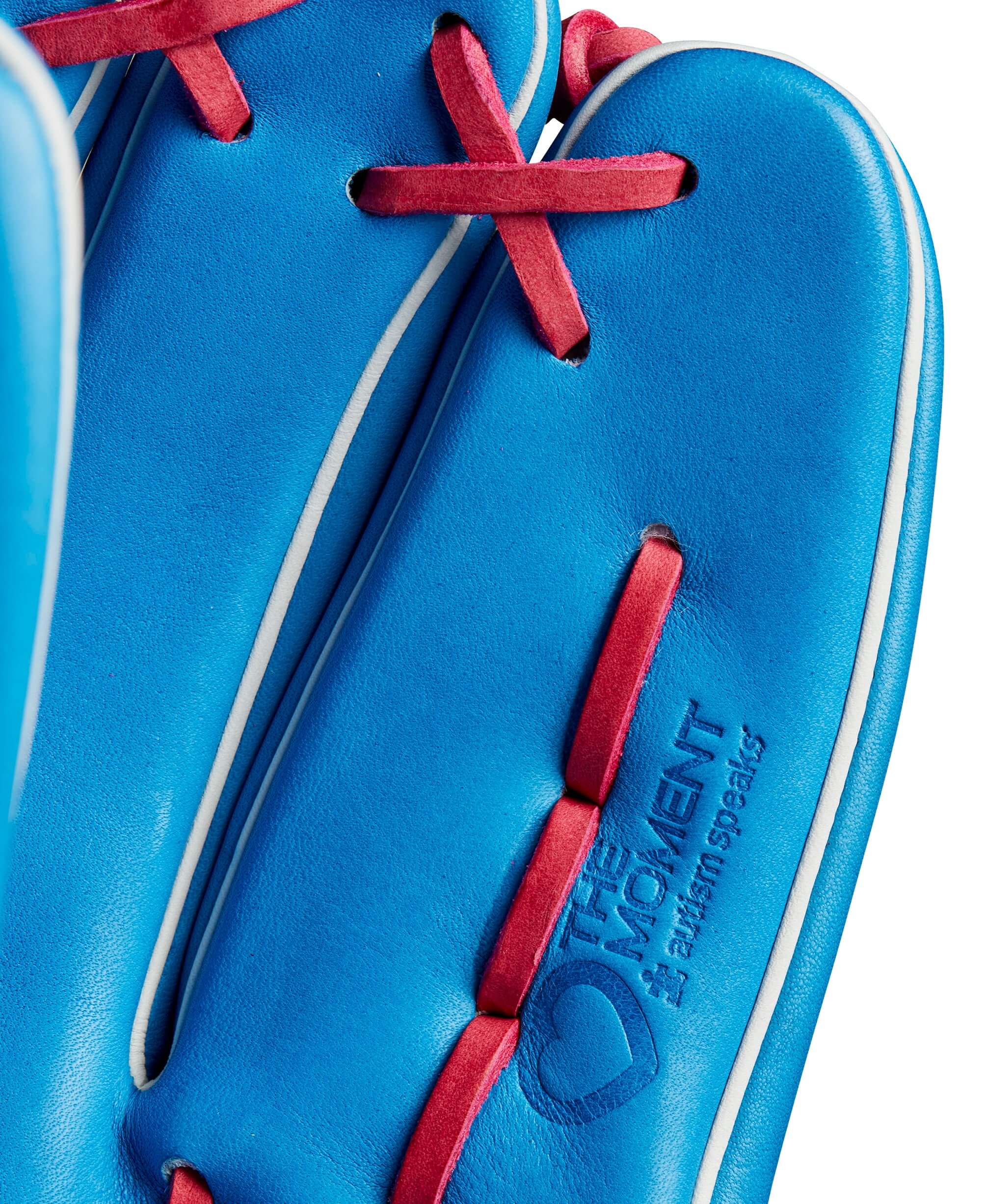 Close-up of Wilson A2000 B2 pitcher’s glove showing Autism Speaks blue leather and pink accents with Love The Moment™ stamp.