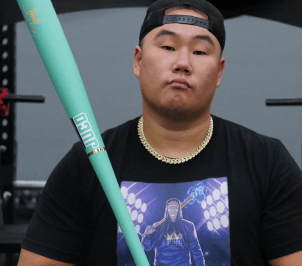 Athlete holding a King Of Juco V.2 Matte Mint Wood Bat in a gym setting, showcasing its design and quality.
