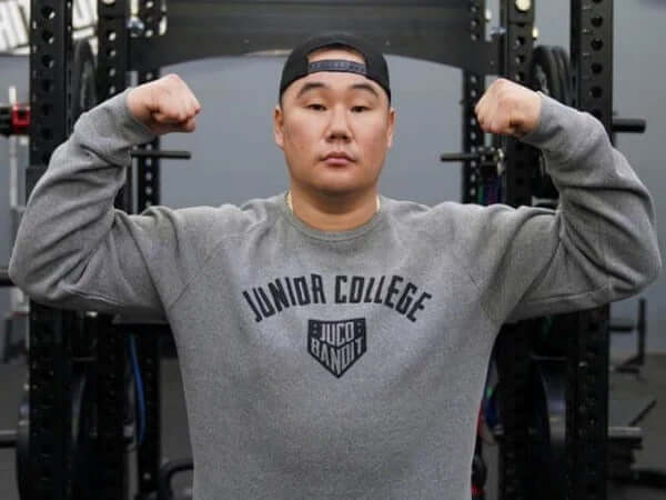 Eric Sim, also known as the "King of JUCO," posing with flexed arms