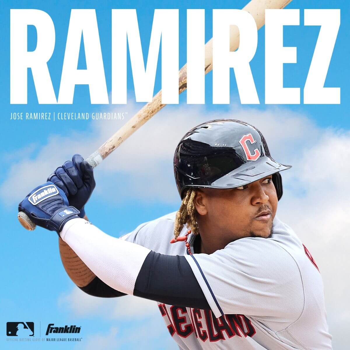 Jose Ramirez of the Cleveland Guardians preparing to bat, wearing Franklin MLB batting gloves against a blue sky background.