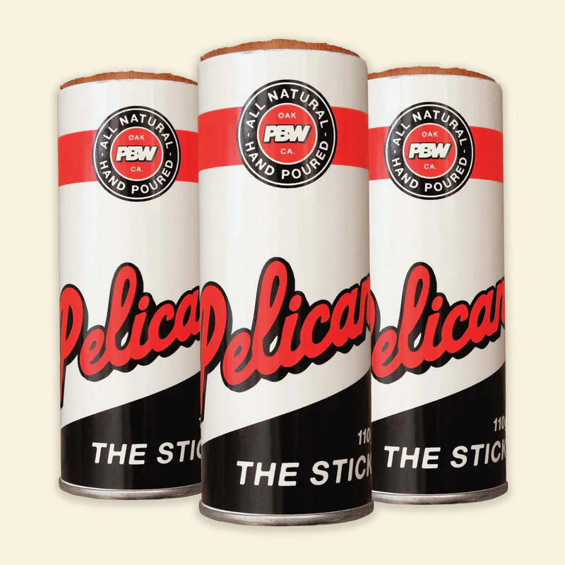 Three cans of Pelican 'The Stick' with red and black branding on a beige background