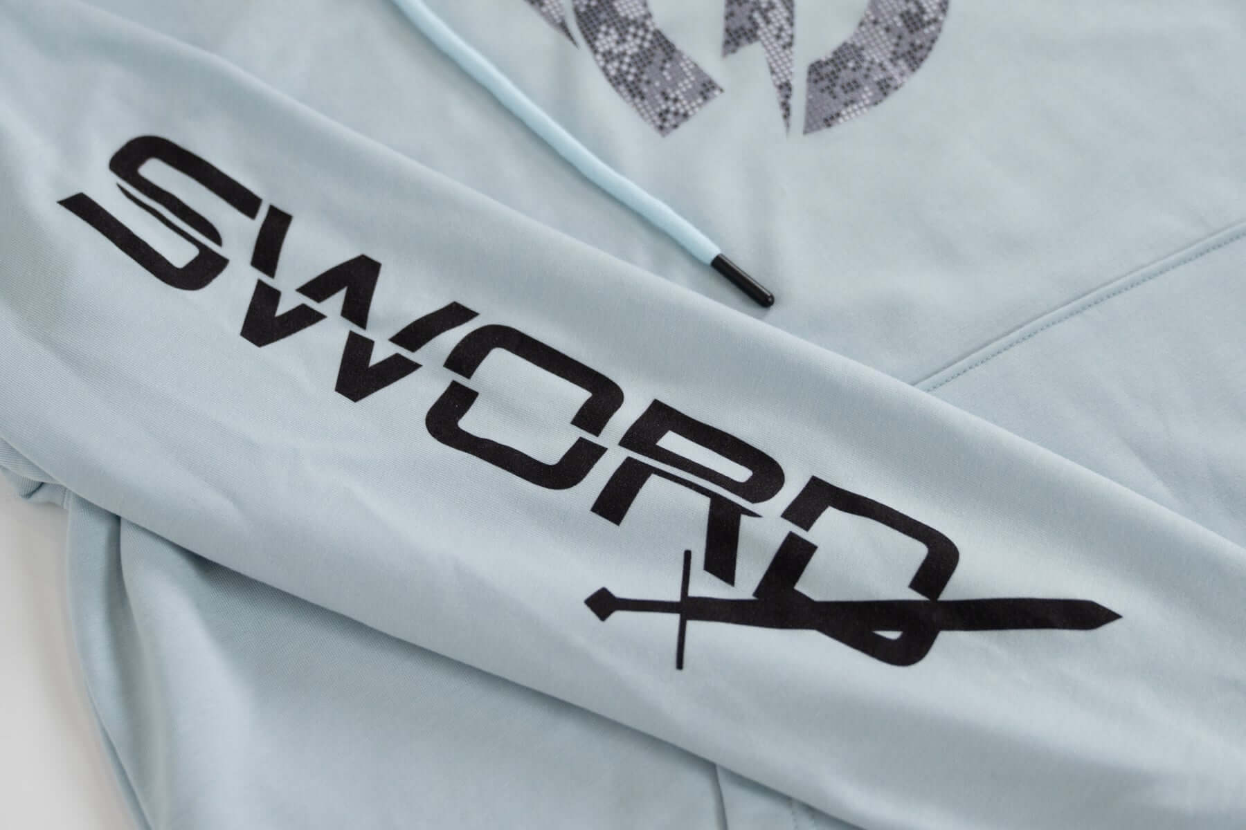 Close-up of the Bauer Outage Blue Lightweight Hoodie featuring 'SWORD' graphic on the sleeve.