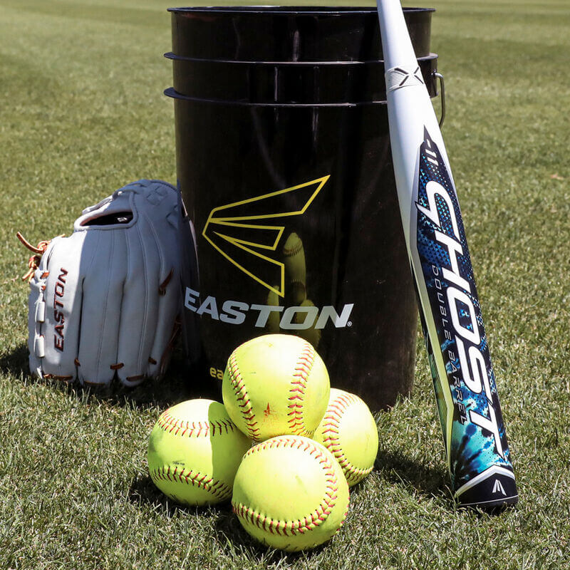 Easton Ghost Tie-Dye fastpitch bat with softballs and glove beside an Easton equipment bucket on grass.