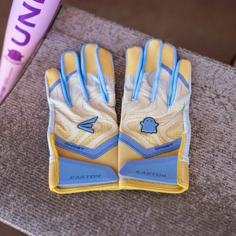 Pair of Womens Ghost Ethos Unlimited Fastpitch Batting Gloves, backhand view, showing blue accents and Ghost logo on a bench.